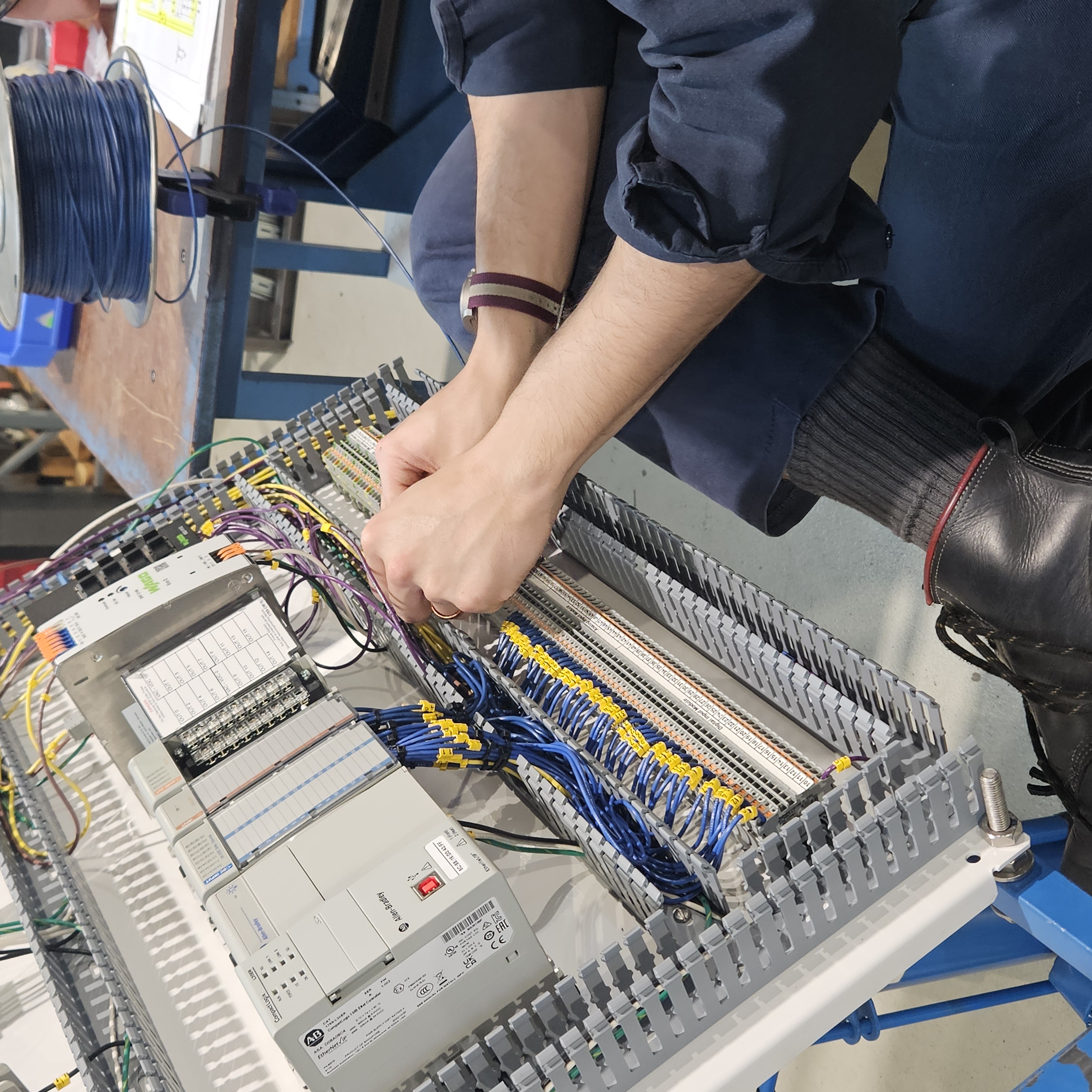 Hands assembling PLC cabinet wiring